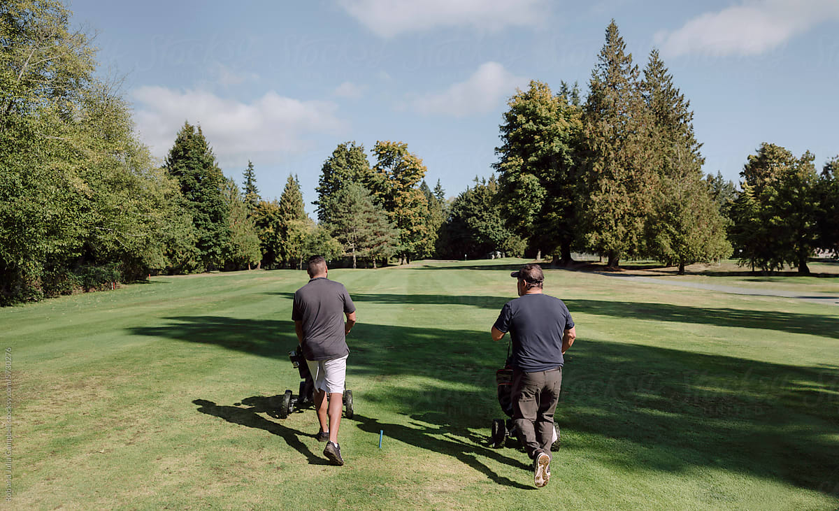Two men walking up golf course fairway.