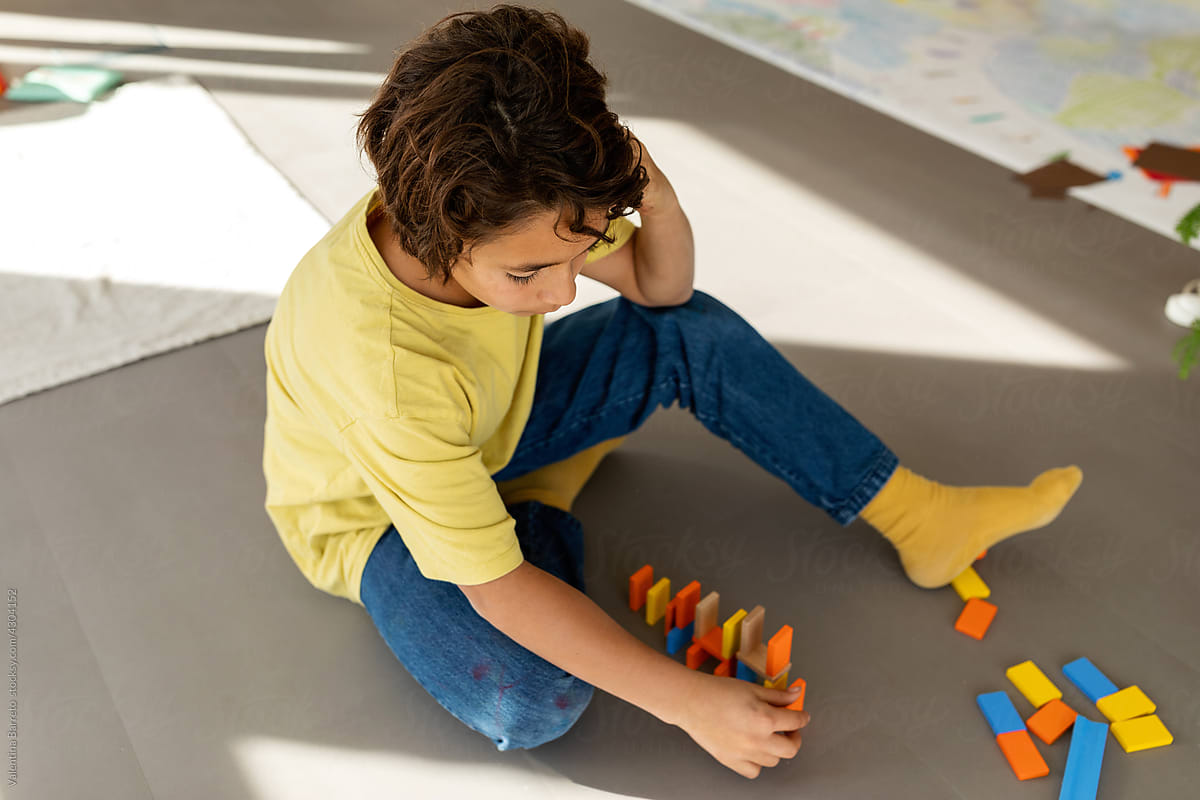 Boy playing with colorful dominoes on the floor