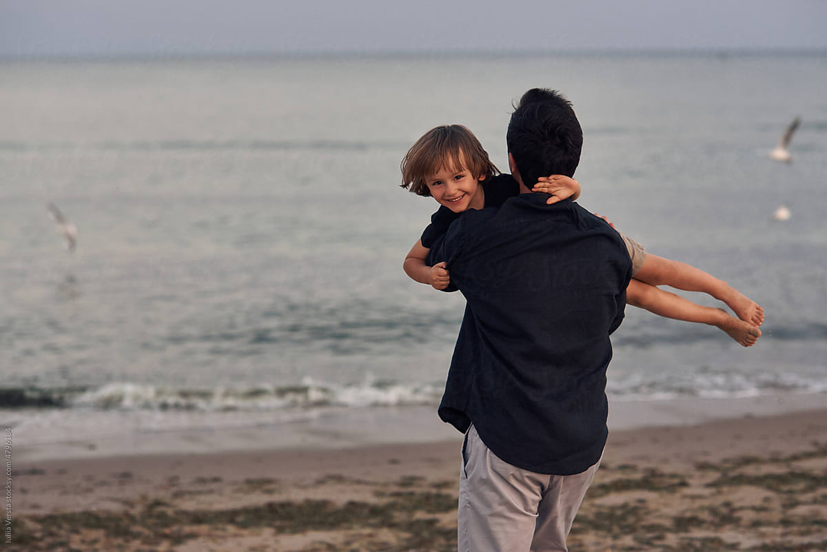 father playing with his son near the sea