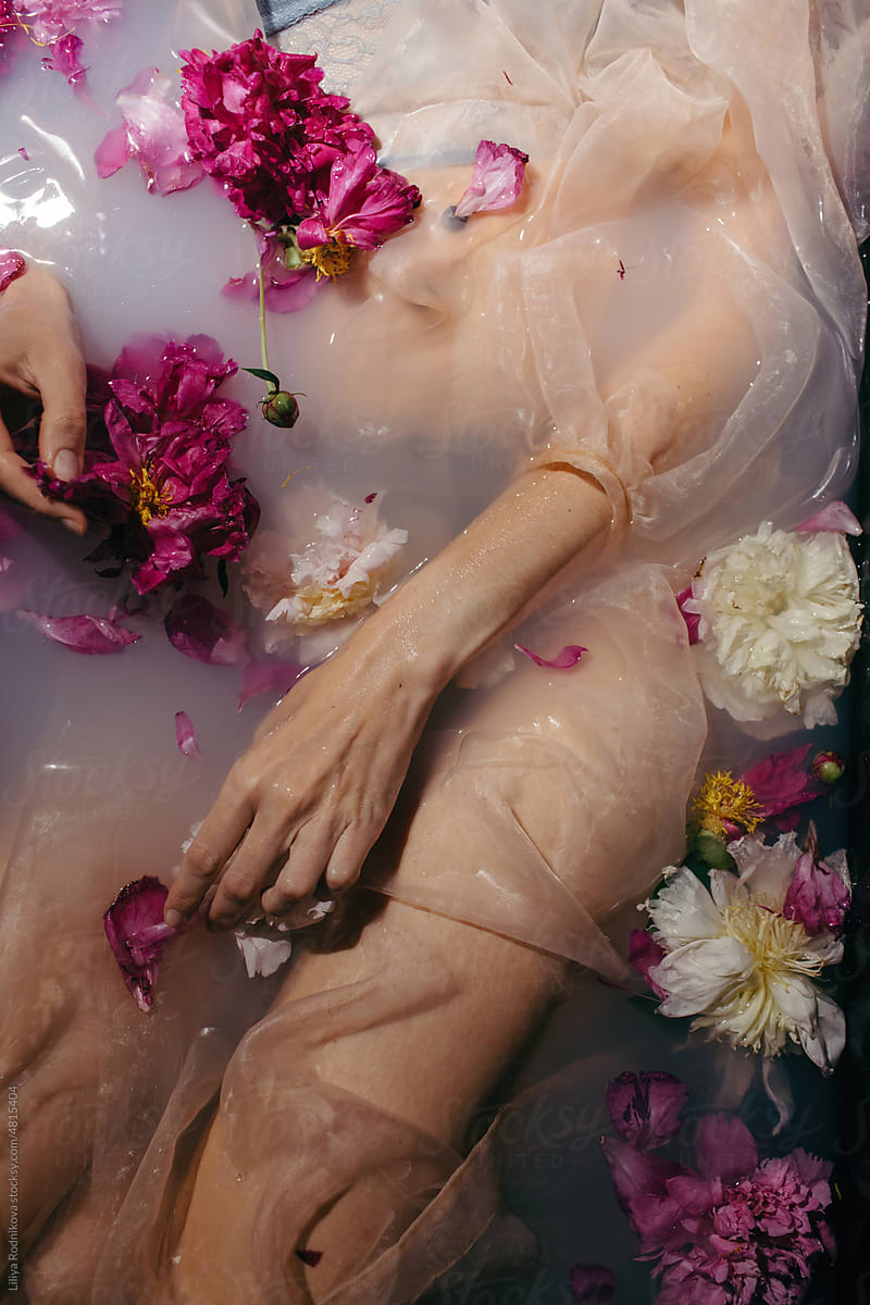 Anonymous sensual woman in milky bath with flowers