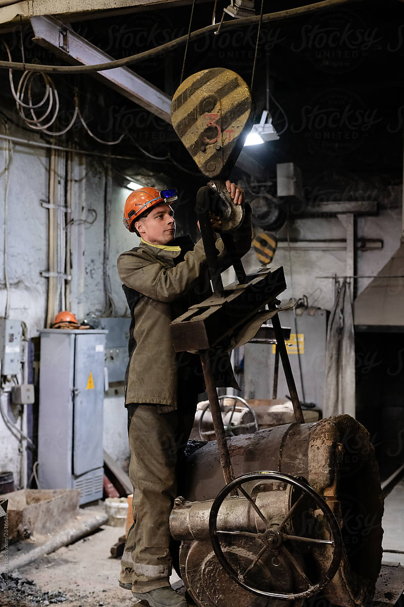 Factory worker hanging crucible on hook