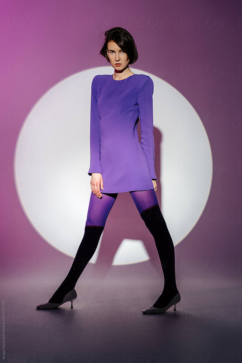 Female model in purple dress standing spreading legs wide