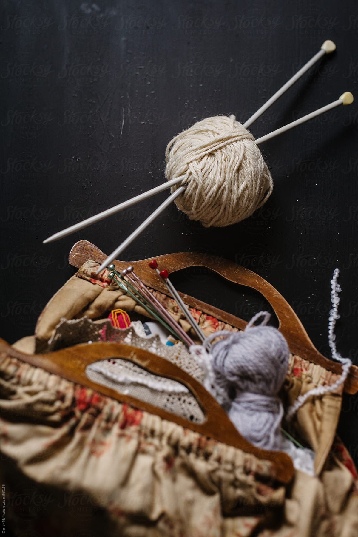 Ball of wool with knitting needles and knitting bag with contents,selective focus.