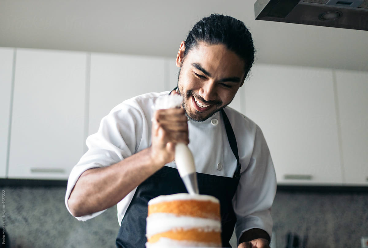smiling pastry chef assembling a cake