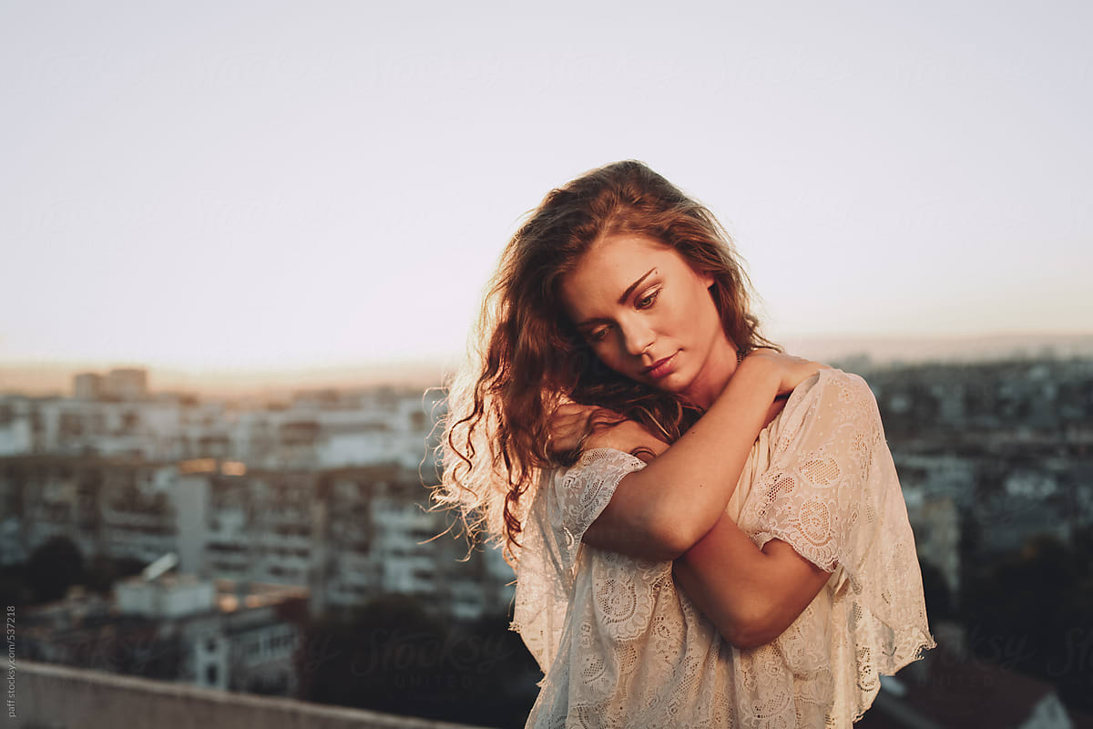 Portrait of a young woman on top of building at sunset