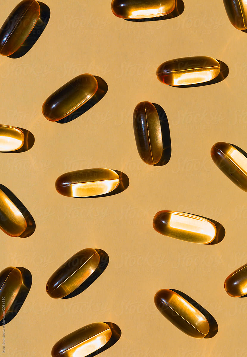 Golden omega 3 capsules on a golden hued background