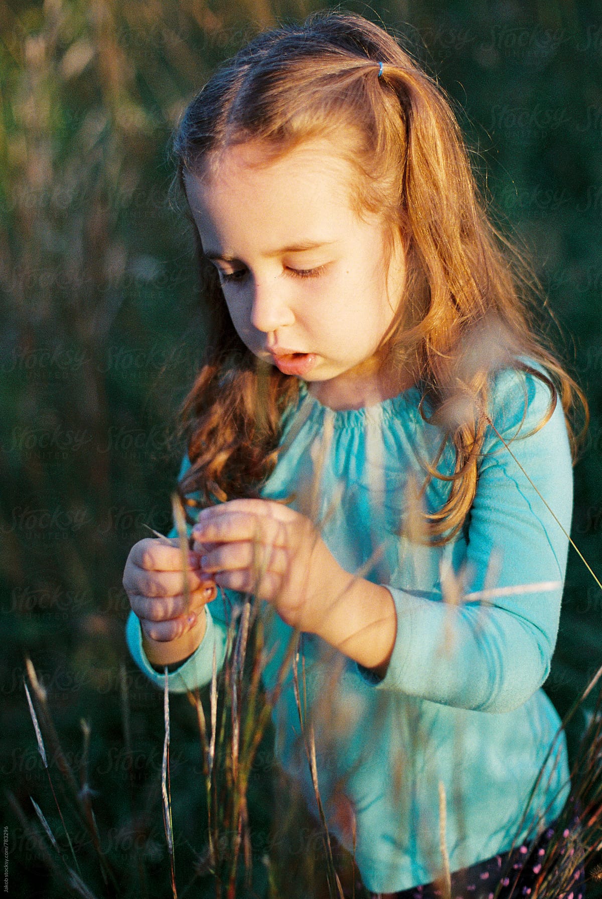 Portrait Of A Beautiful Young Girl Playing In A Field Of Tall Grass 