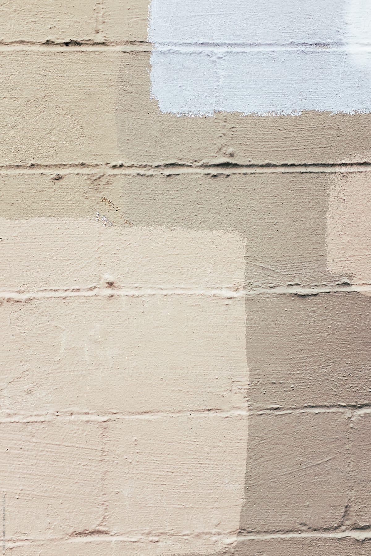 Close up of brown and grey paint covering graffiti tags on brick wall