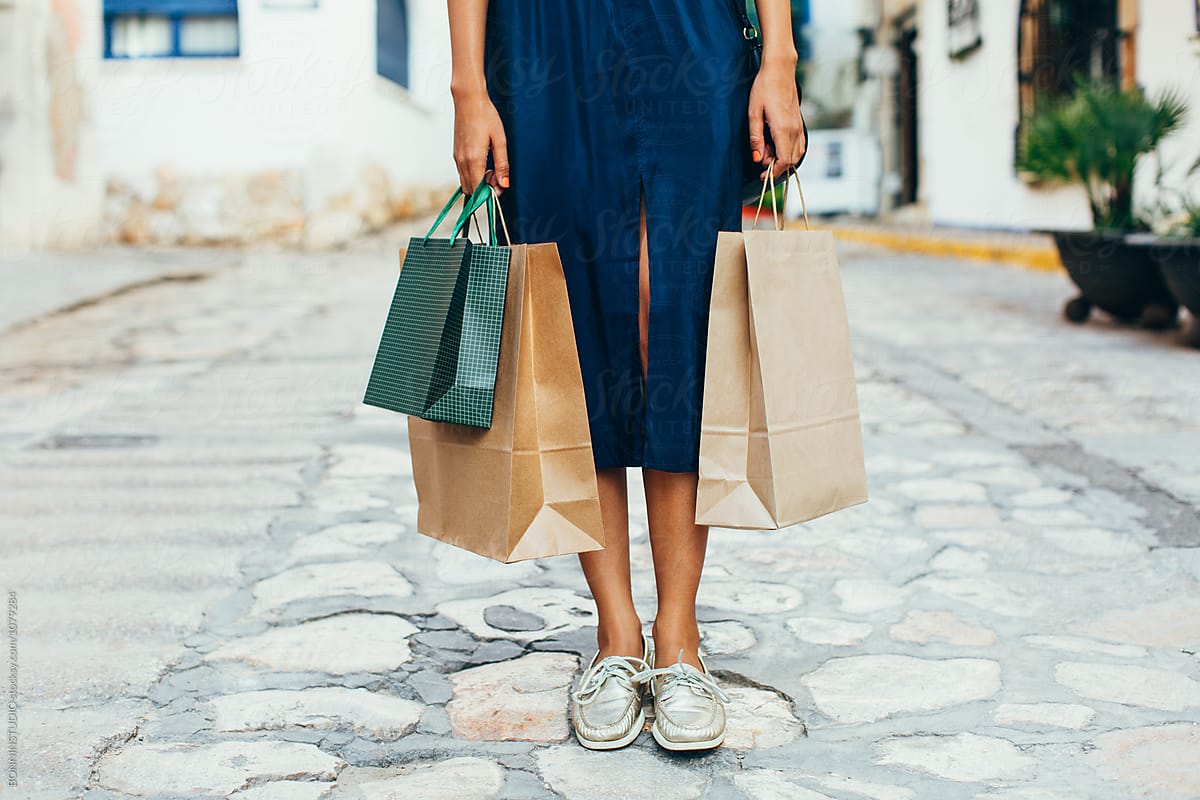 Closeup of a woman holding shopping bags on the street.