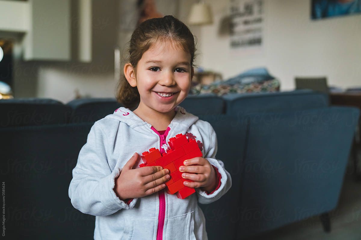 Happy Little Girl Holding a Red Heart Made of Blocks Toys