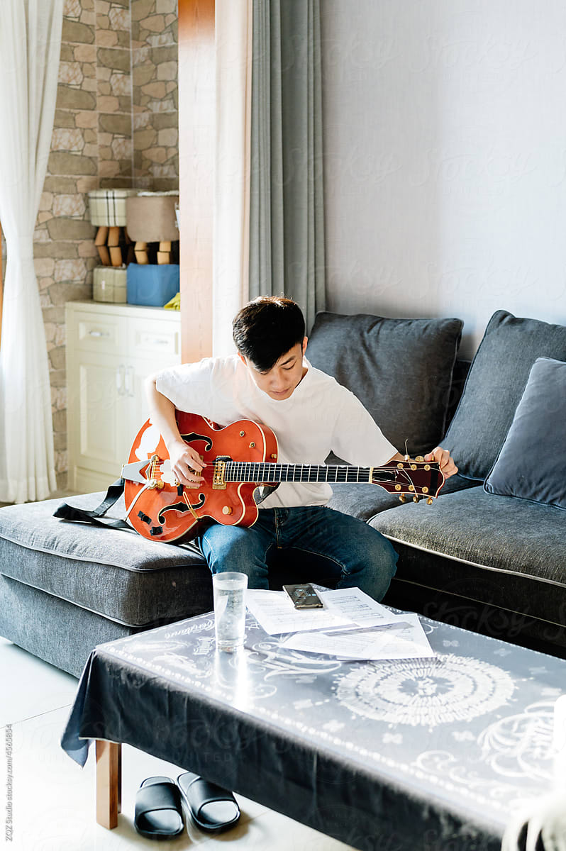 Young man playing guitar at home