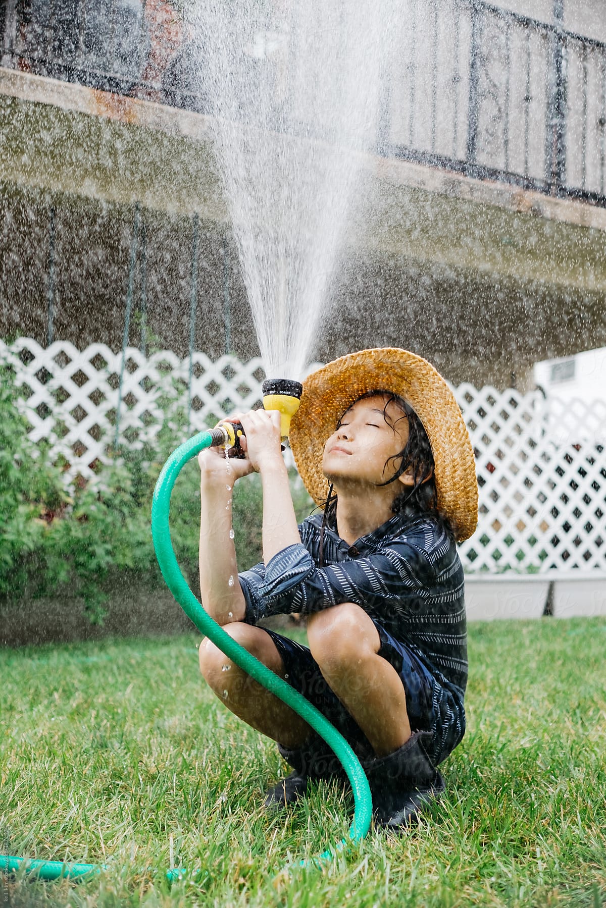 Young boy playing with garden hose in backyard