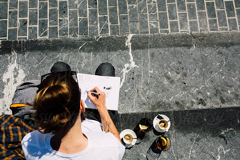 Above view of. a man drawing and drinking coffee