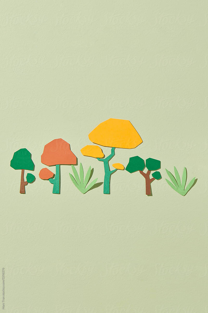Colorful trees cut from paper on green pastel background