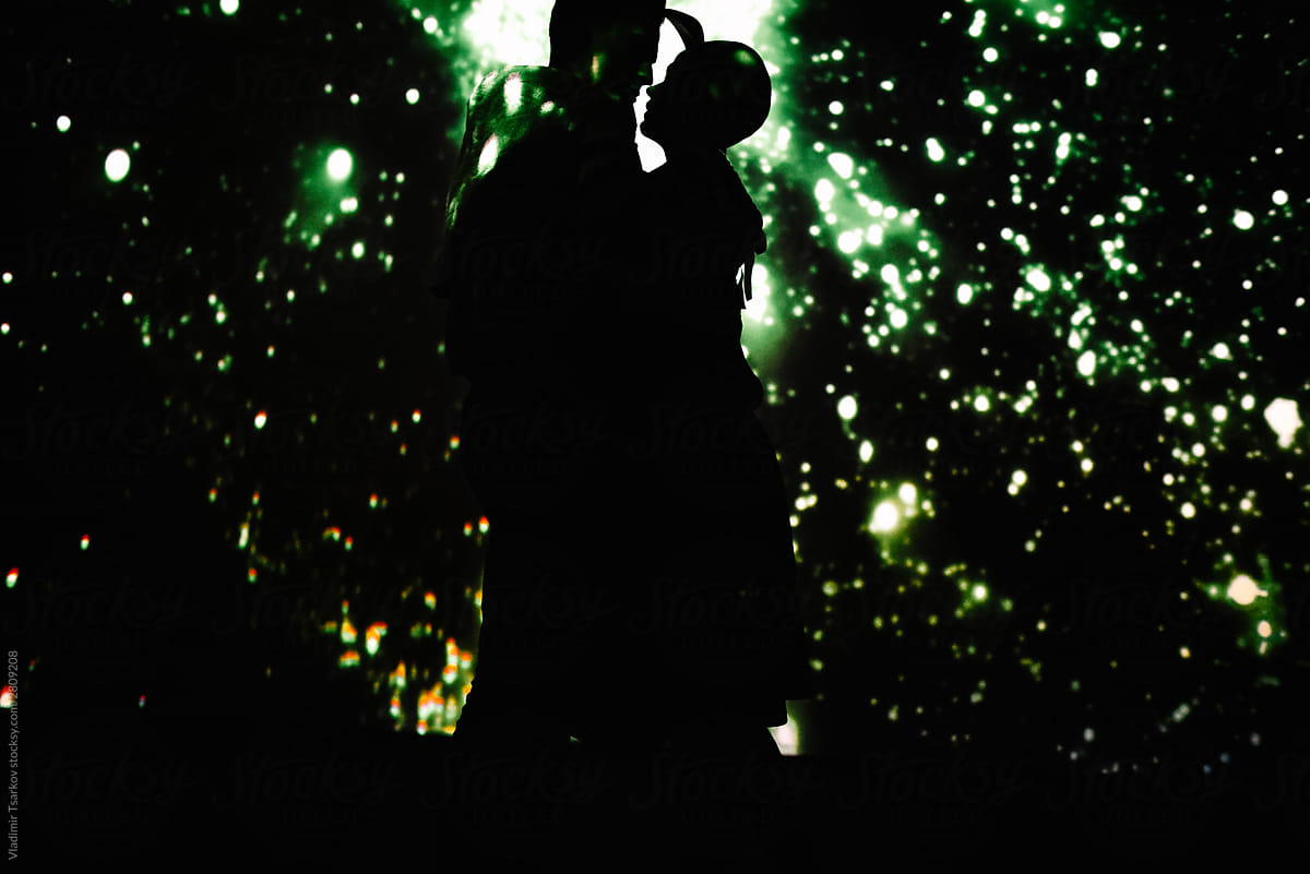 Anonymous romantic couple on background with projection of starry sky