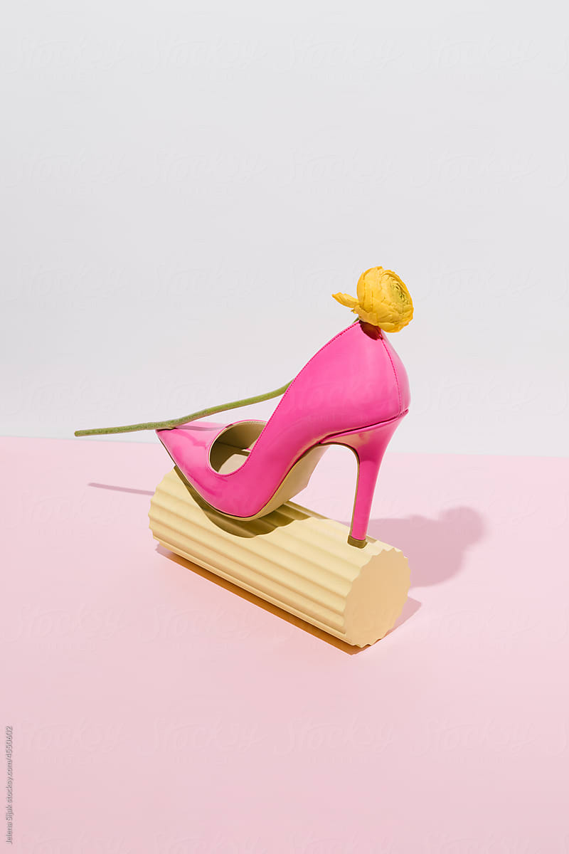 One pink stiletto shoe with a yellow flower, on bright pink background