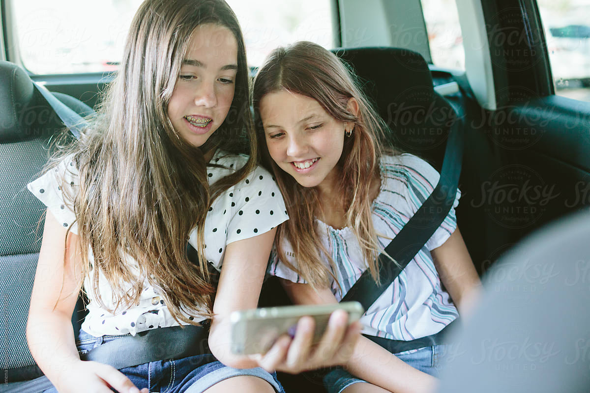 two teenage girls looking at a phone in a car