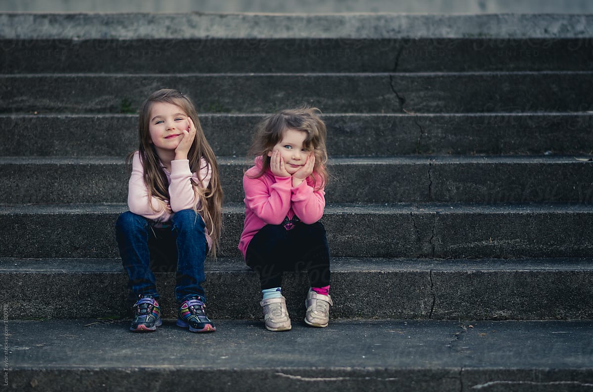 Cute Sisters Sitting On Steps