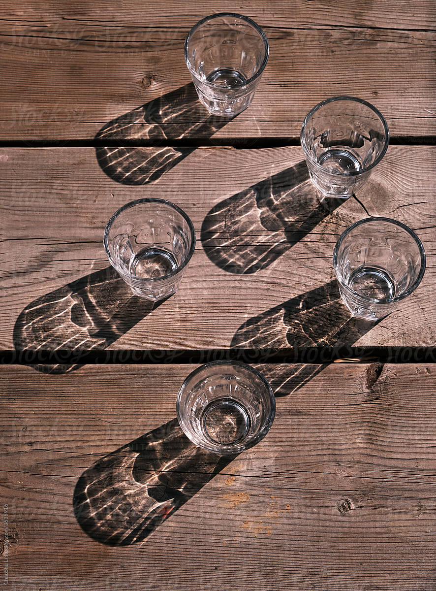 Empty drinking glass on old wooden table in sunligh