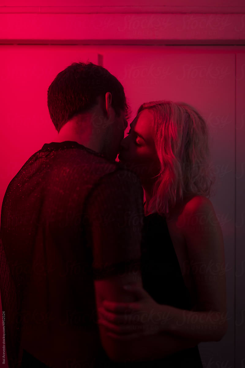 Intimate portrait of kissing couple under red light