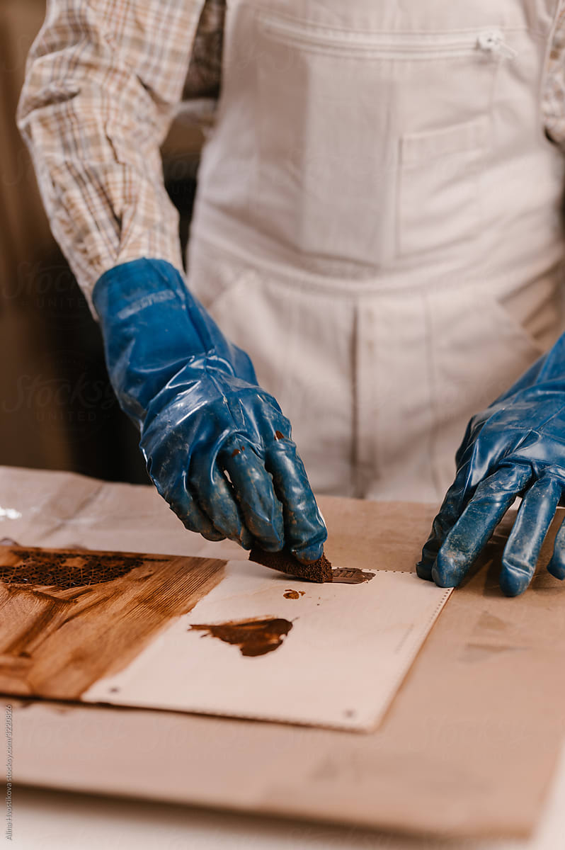 Carpenter staining wooden handicraft on table