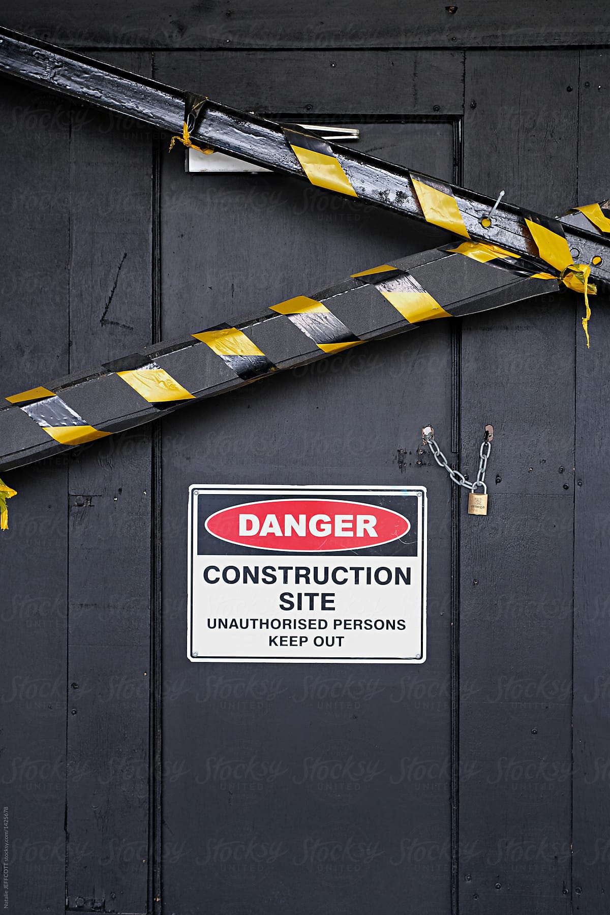 Close up of do not enter construction zone and danger sign on black wall with tape