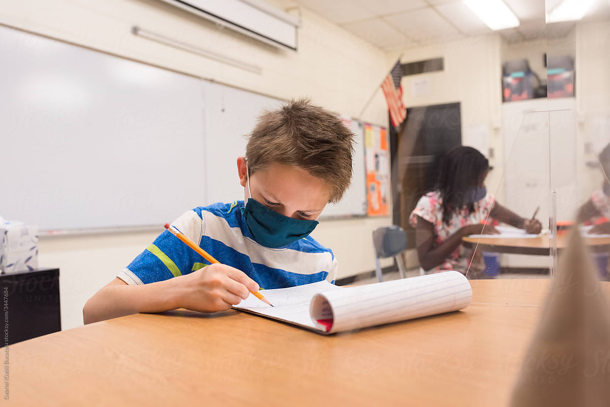 Boy wearing a mask working in the classroom