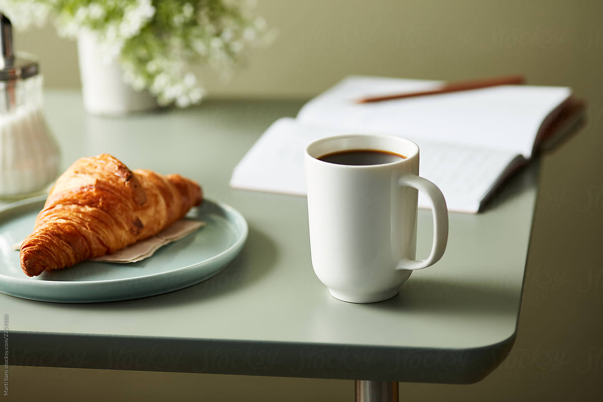 Fresh croissant and cup of coffee on the table.