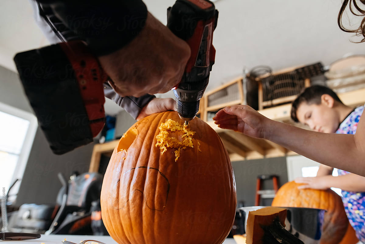 Using power drill to carve pumpkin.