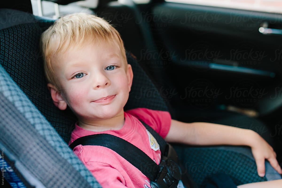 little boy making faces in his carseat