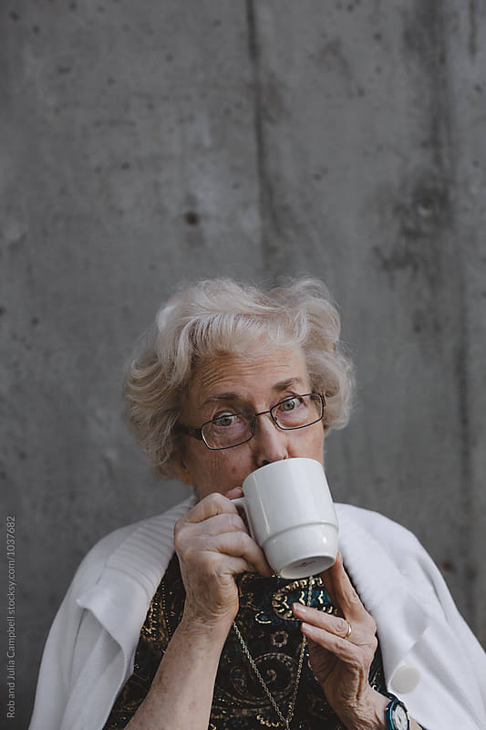 Funny portrait of senior caucasian woman hiding behind coffee mug