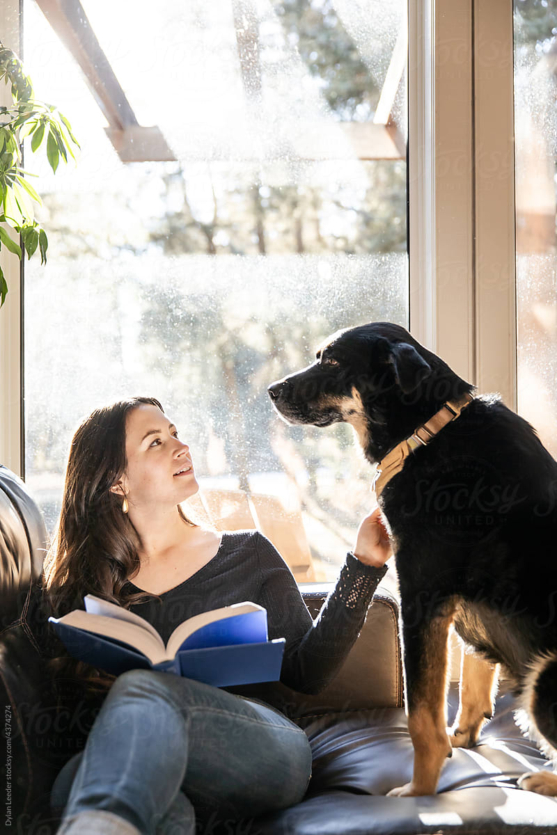 A Woman Stops Reading To Pet Her Dog