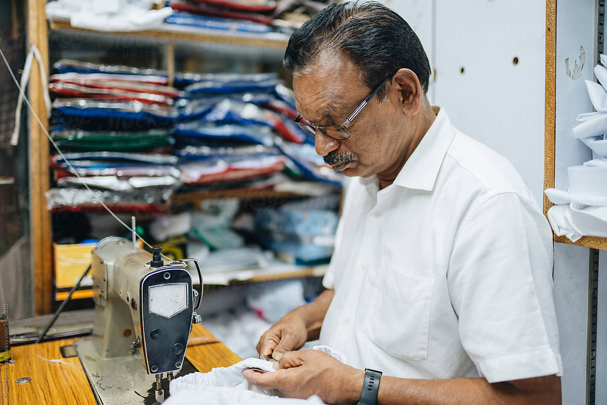 Concentrated Indian tailor sewing clothes in atelier