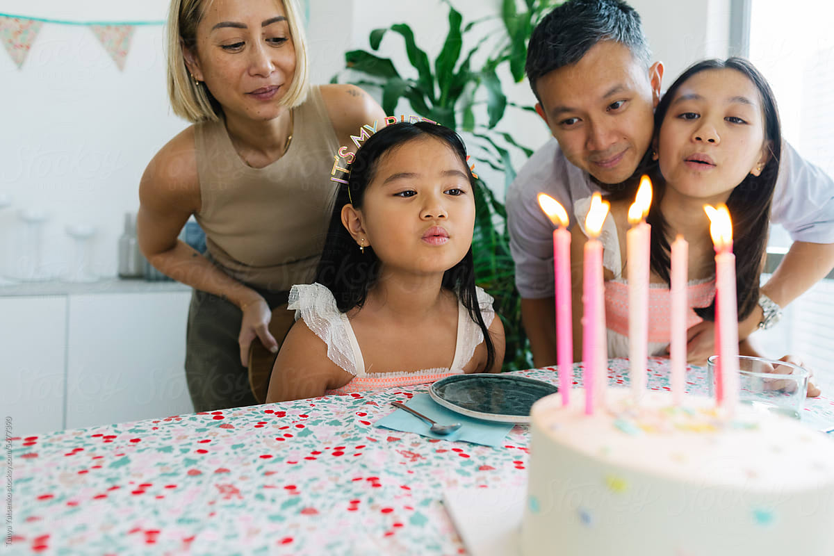 A girl blowing candles on a birthday cake.