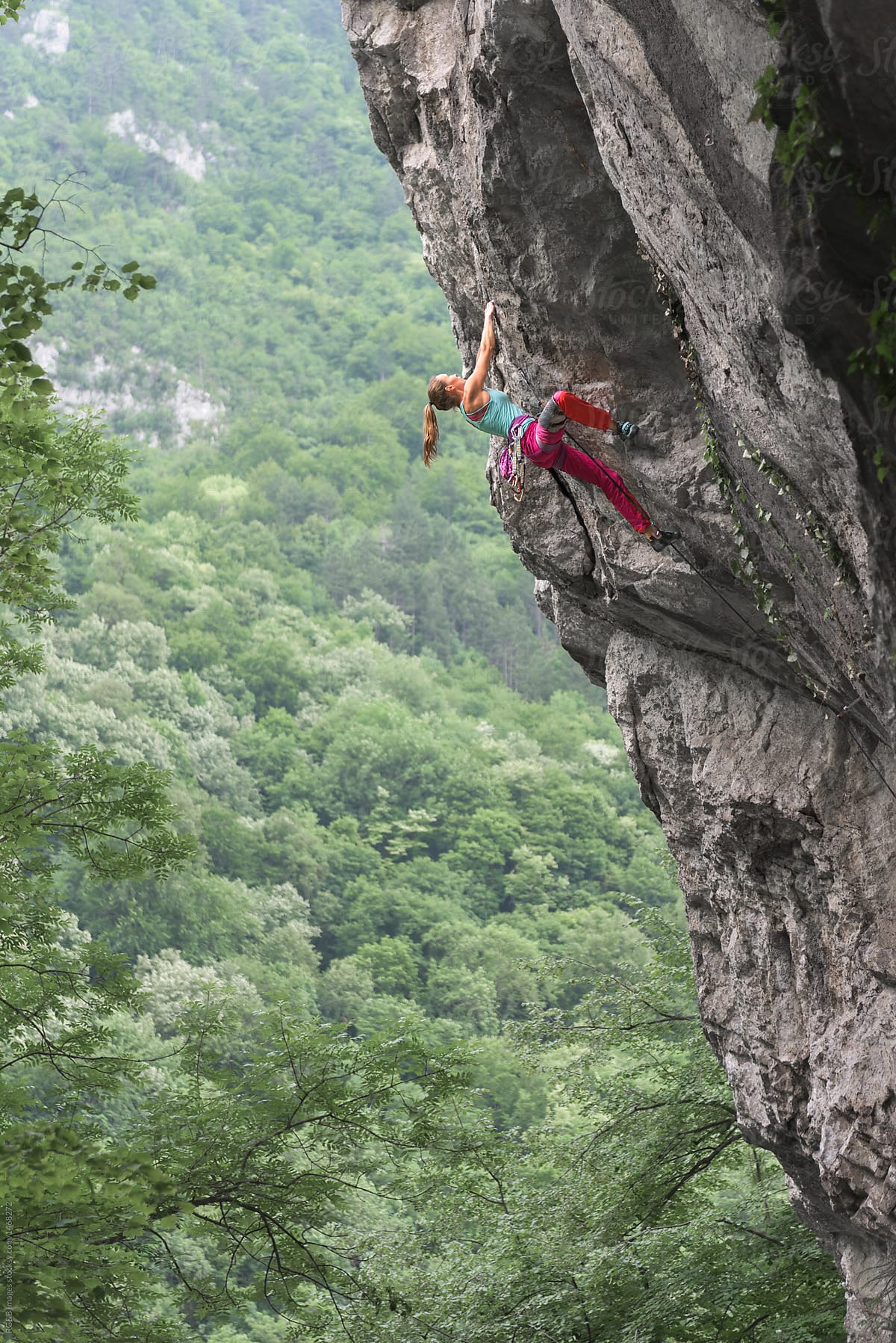 Side view of woman rock climbing on craggy rock facade