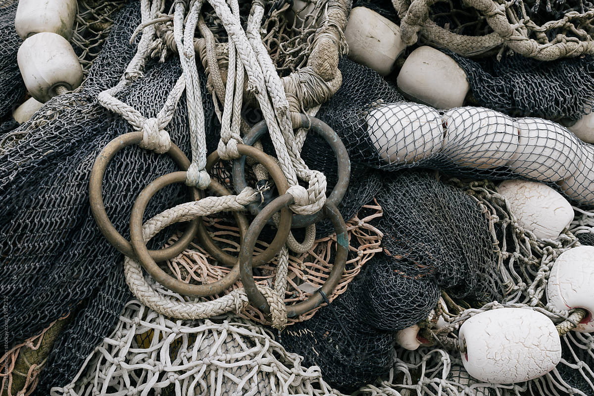 Pile Of Green Fishing Nets, Ropes And Chains By An Old Fence by Stocksy  Contributor Lior + Lone - Stocksy