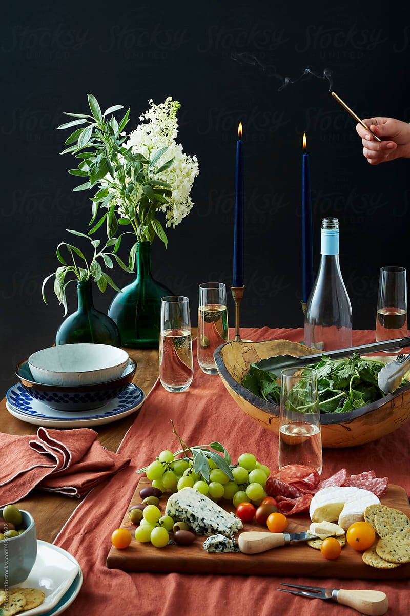 A hand lights two candles at a table set for entertaining