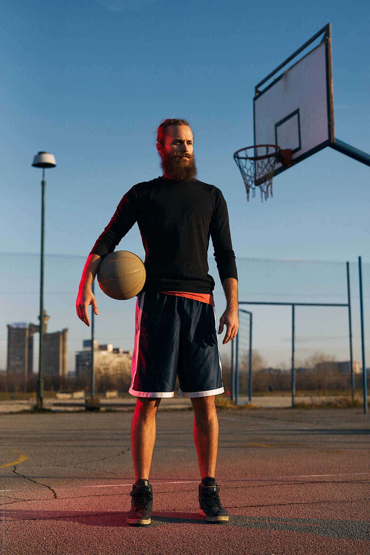 Portrait of street basketball player on the pitch holding ball.