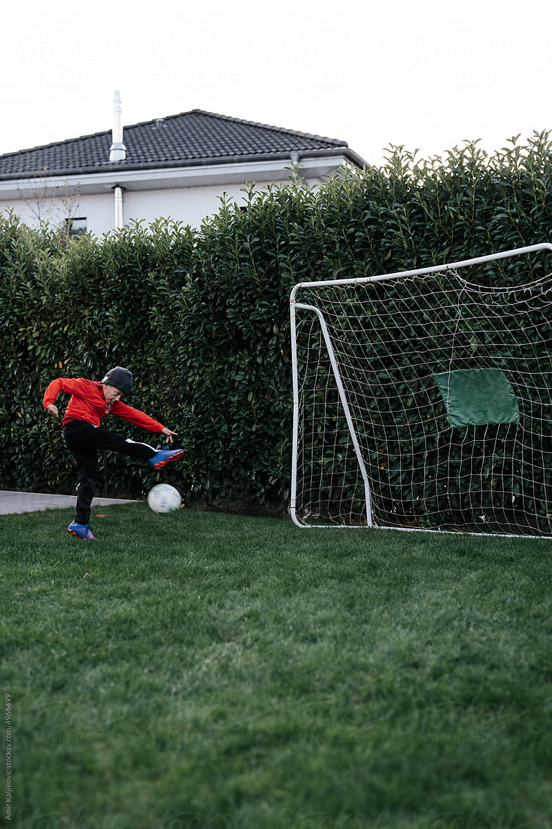 Young boy playing soccer in his garden
