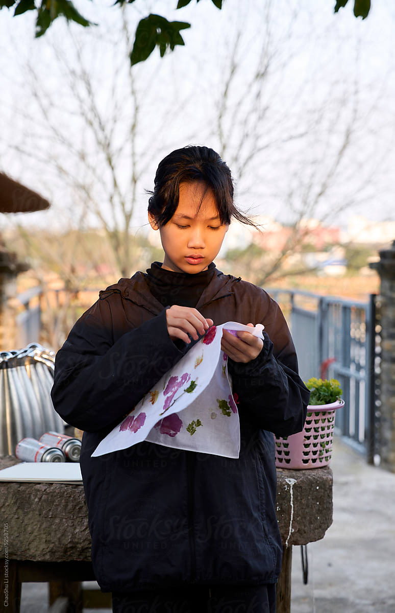 Asian girl is dyeing silk cloth, in the yard in the afternoon