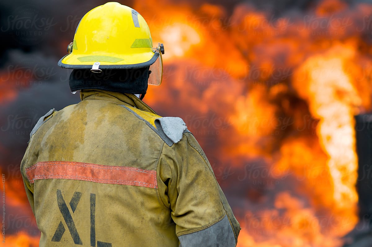 A firefighter faces a wall of flames