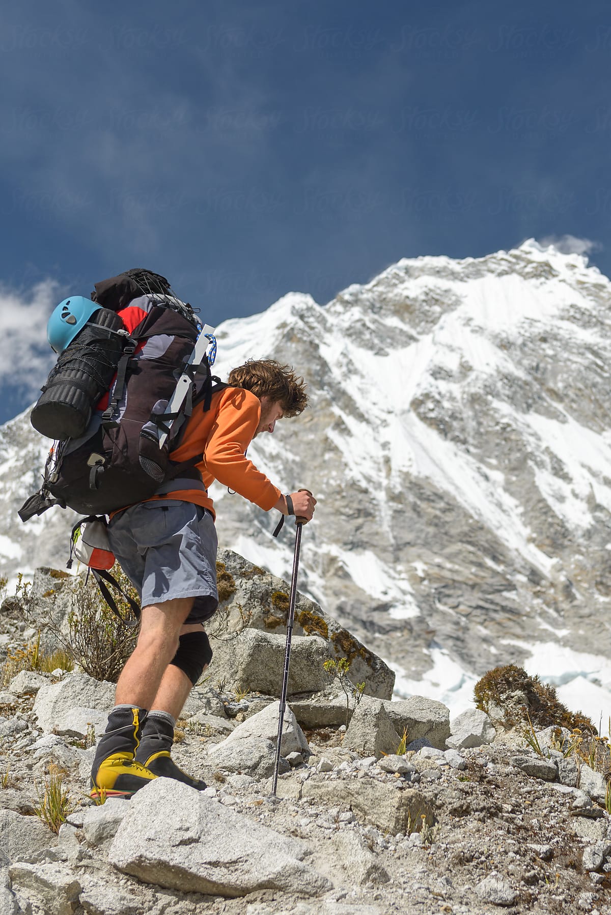 Mountaineer carrying heavy backpack hiking at high altitude