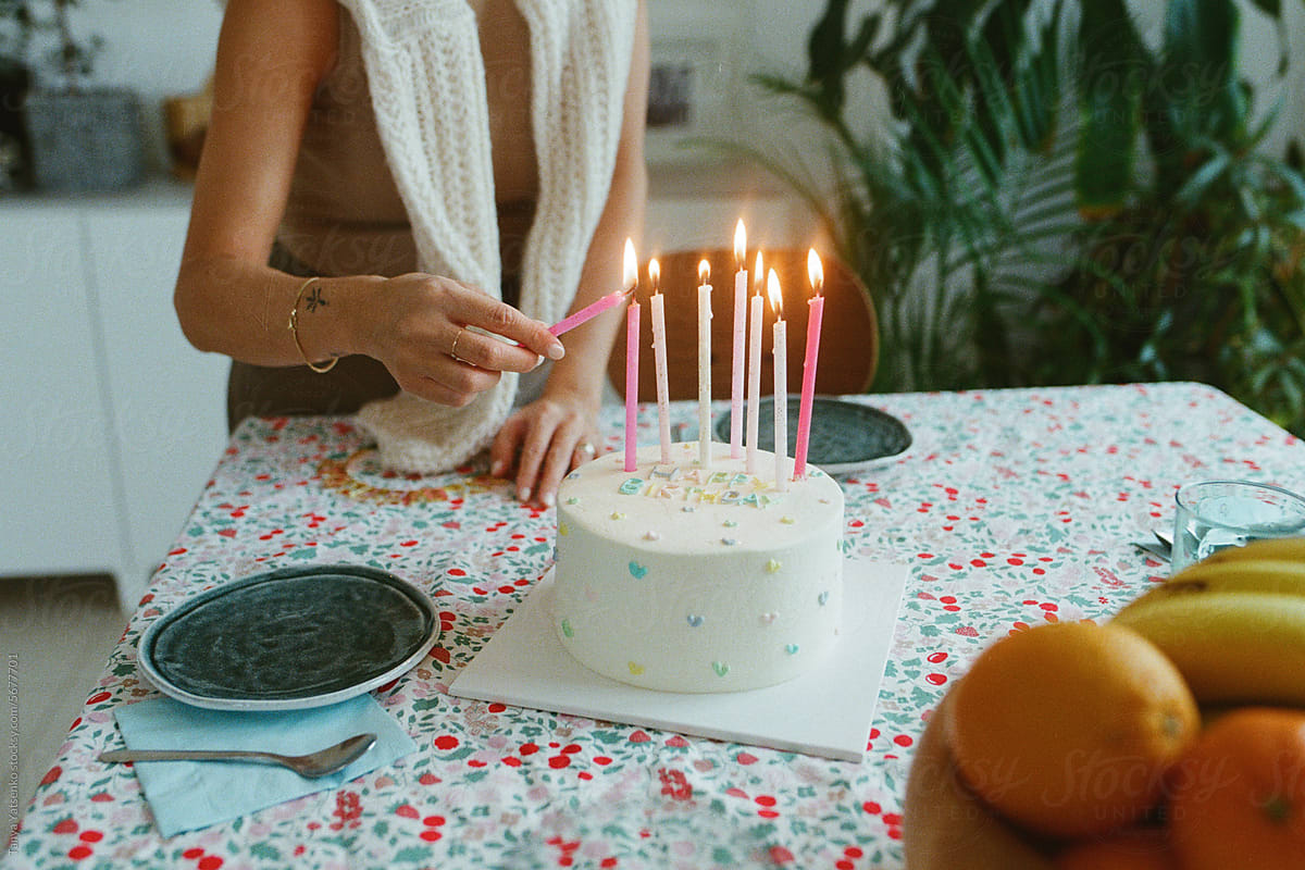 A woman lighting up candles on a cake