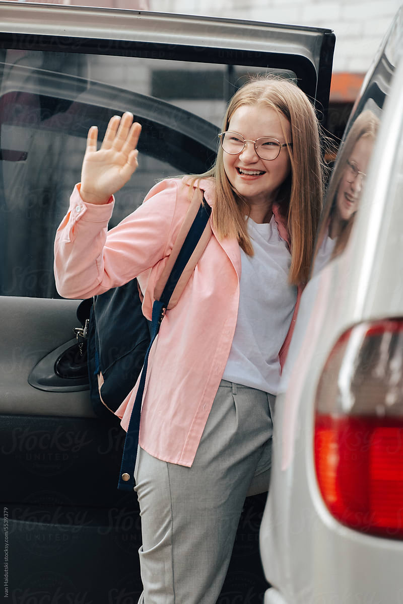 Portrait of teenager schoolgirl waving goodbye on the way to school