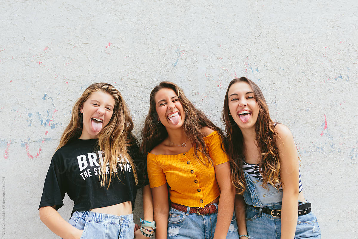 Studio Portrait Of Cute Teen Girls Sticking Out Tongue by Stocksy