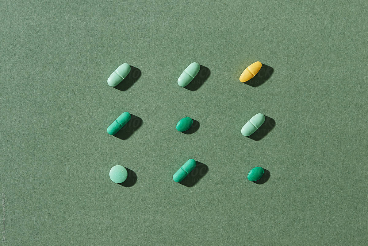 Different colorful pills on green background