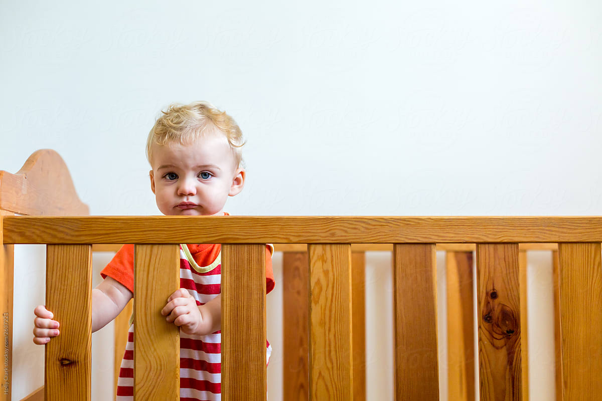 Baby holding bars of crib