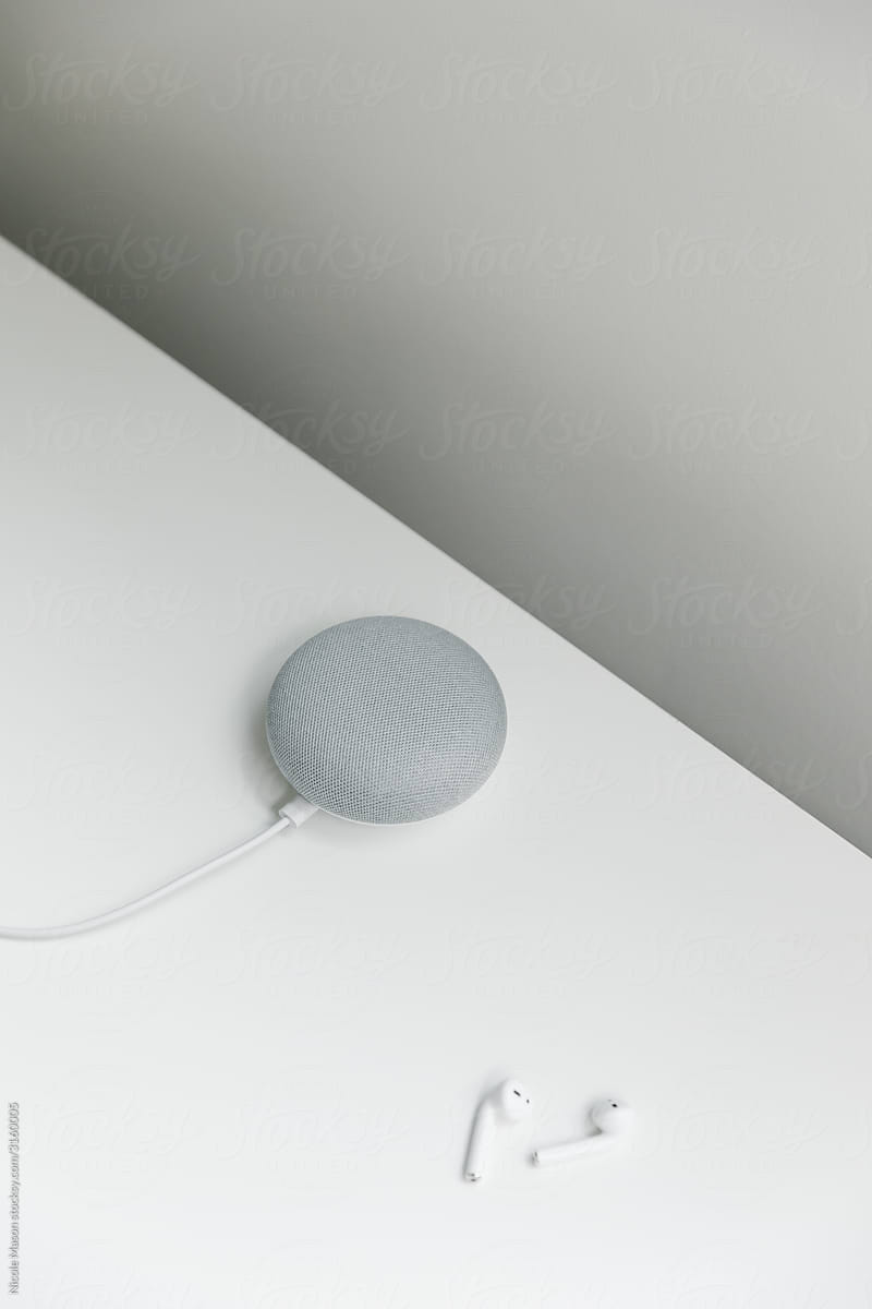 modern smart speaker and wireless headphones on white table
