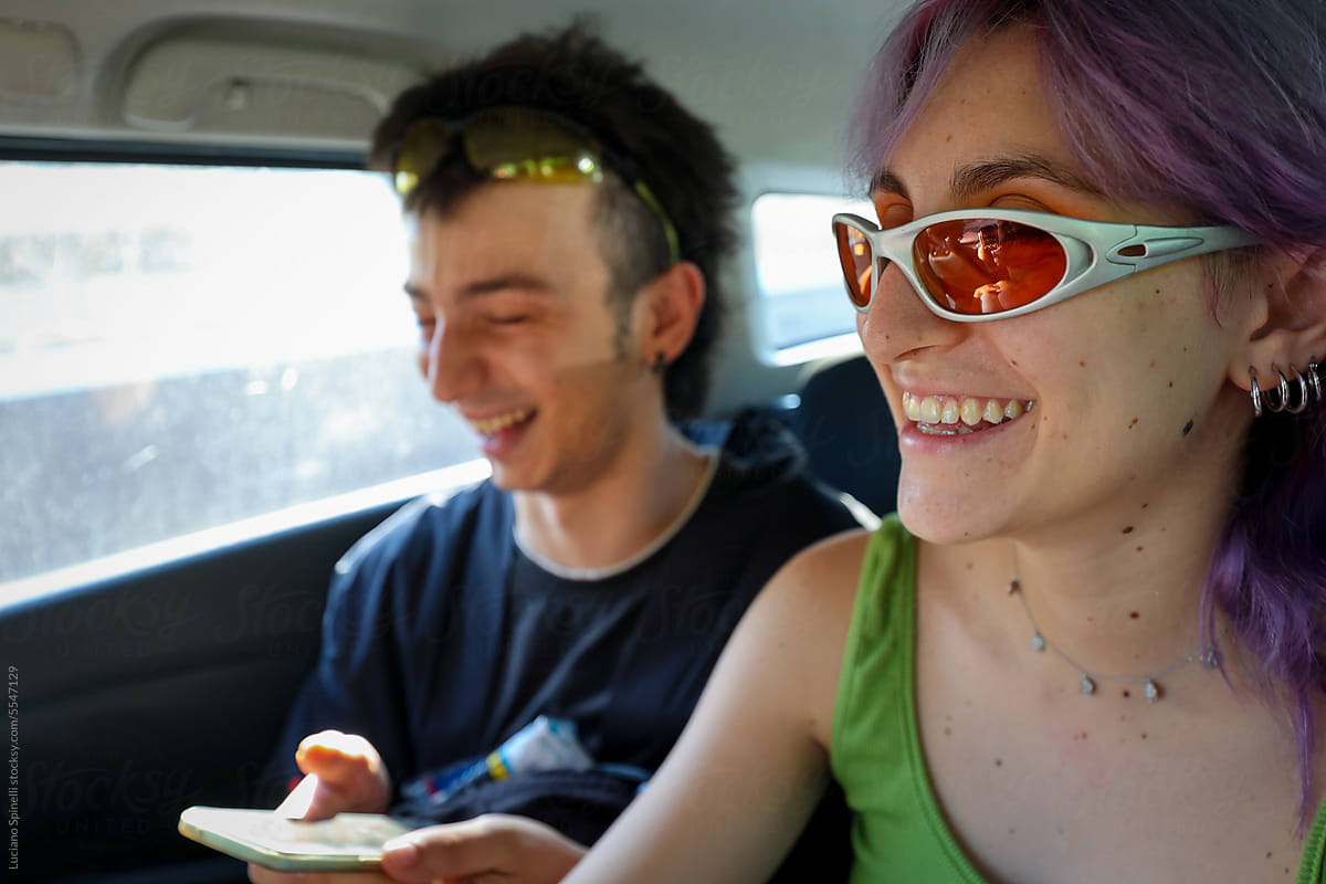 Cool Generation Z friends texting and laughing inside car