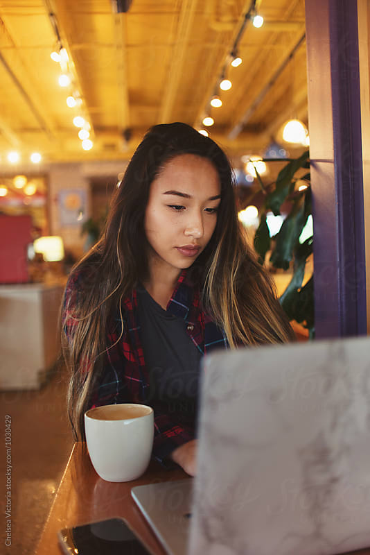 A young woman on a laptop at a cafe